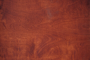 Rich mahogany surface with grain patterns and warm tones in light