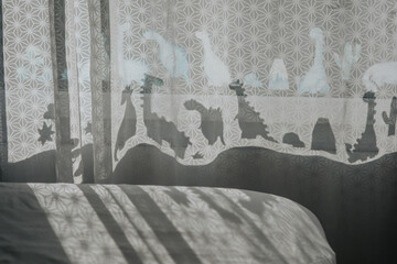 Nursery room with dinosaur shadows on curtain.