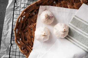 Fresh garlic bulbs on a kitchen counter in a woven basket with linen