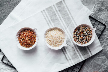 Different seeds displayed in small bowls on a kitchen towel during meal prep