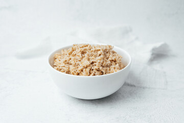 Cooked brown rice in a white bowl on a light background for healthy meals