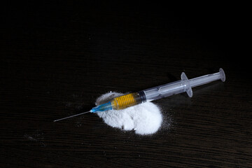 syringe on a handful of white powder resembling a narcotic. The concept of stopping drug addiction