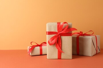 Many gift boxes wrapped in kraft paper on orange table. Space for text
