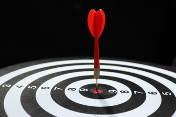 Targeting. Dart board with arrow on black background, closeup