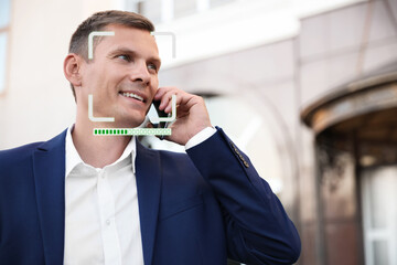 Facial recognition system identifying smiling man talking on smartphone outdoors