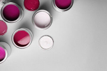 Cans with paint in shades of pink on light grey background, top view. Space for text