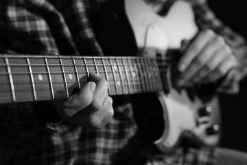 Fototapeta premium Woman playing guitar in darkness, closeup. Black and white effect