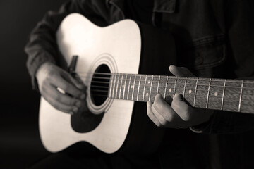 Man playing guitar in darkness, closeup. Black and white effect