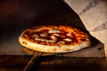 Hot pizza on a metal peel being taken out of the oven after baking. traditional cooking context.