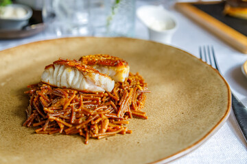 Exquisite cod filet with golden crust served over authentic Spanish vermicelli pasta fideua on...