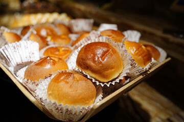 Freshly baked round buns in a basket on a wooden table.
