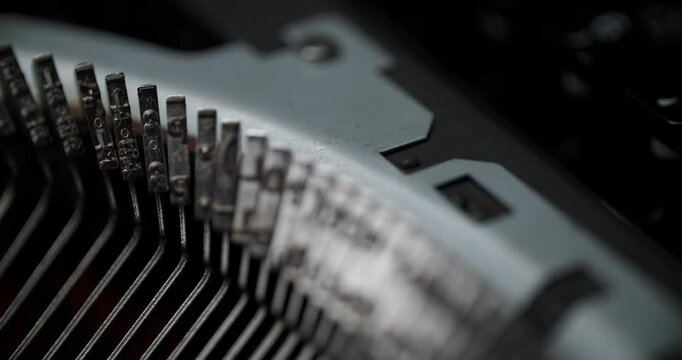 Extreme close-up of vintage typewriter keys showing intricate metal details. Blurred industrial background highlights mechanical textures in muted monochromatic tones.