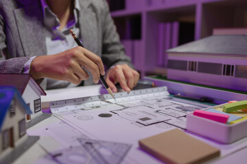 a beautiful female architect is working in her private office because she needs to concentrate on improving the blueprints to be in accordance with the law, engineer, foreman, contractor