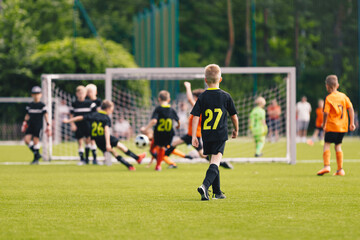 Obraz premium Youth Soccer Match in Action. Kids Competing Near the Goal on a Sunny Day