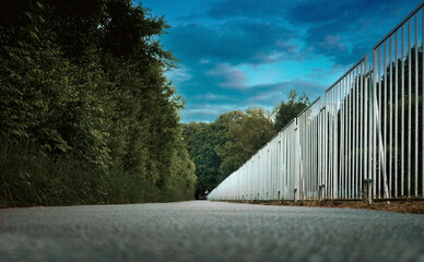Promenade next to the white fence and the park