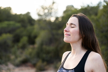 Woman with her eyes closed breathing fresh air and meditating