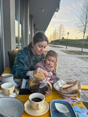 Caucasian woman feeding her son in a street cafe. 