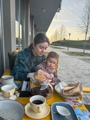 Gordijnen Caucasian woman feeding her son in a street cafe.  © Михаил Решетников