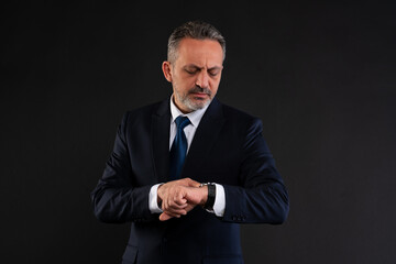 Businessman checking wristwatch on dark background.