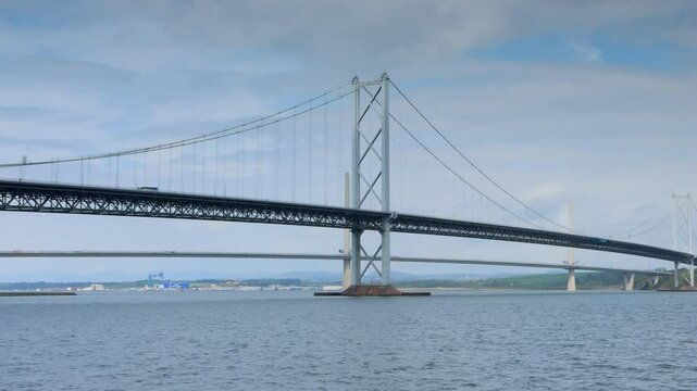 Slow pan of the Forth Road Bridge and Queensferry crossing spanning the 'Forth of firth' in Scotland
