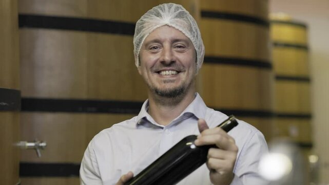 winemaker : winemaker hold bottle of wine check process of make wine. Wooden wine barrels or cognac barrels in the cellar of the winery