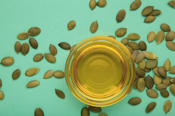 Pumpkin seed oil and seeds on mint background.