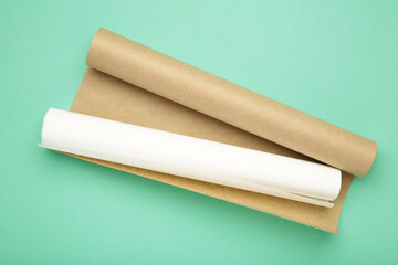 Rolls of white and brown baking paper on mint background