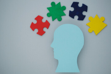 Silhouette of a blue head with colorful puzzle pieces on gray background. The concept of mental health and the formation of an inclusive society. top view