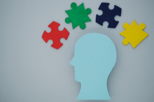 Silhouette of a blue head with colorful puzzle pieces on gray background. The concept of mental health and the formation of an inclusive society. top view