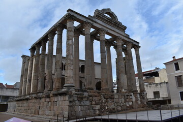 Obraz premium Roman temple ruins in Mérida with well-preserved stone columns and a partially cloudy sky, showcasing ancient architecture and historical significance 