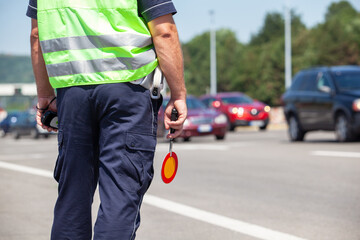 Police officer wearing a reflective vest conducts roadside inspections, managing vehicle flow and ensuring safety. Traffic control concept.