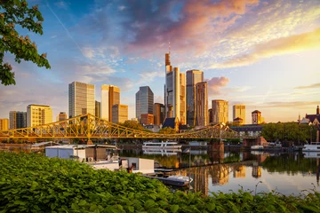 Golden sunrise view of the skyline of Frankfurt am Main, Germany, with banking skyscrapers, Eiserner Steg Bridge and River  © moofushi