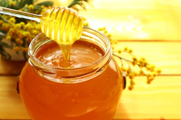 Honey dripping and glass jar full of honey                               