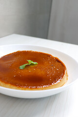 Delicious caramel custard with a glossy caramel top, served on a white plate. Perfectly lit, smooth texture, and minimal background. ideal for menus, blogs, packaging, or dessert features. Copy space