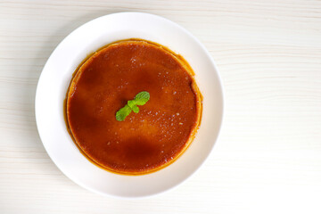 Delicious caramel custard with a glossy caramel top, served on a white plate. Perfectly lit, smooth texture, and minimal background. ideal for menus, blogs, packaging, or dessert features. Copy space