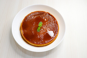 Delicious caramel custard with a glossy caramel top, served on a white plate. Perfectly lit, smooth texture, and minimal background. ideal for menus, blogs, packaging, or dessert features. Copy space