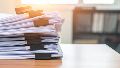 Unfinished documents stacked neatly on desk, showcasing busy work environment filled with paperwork and organization. sunlight adds warm touch to scene, enhancing atmosphere of productivity