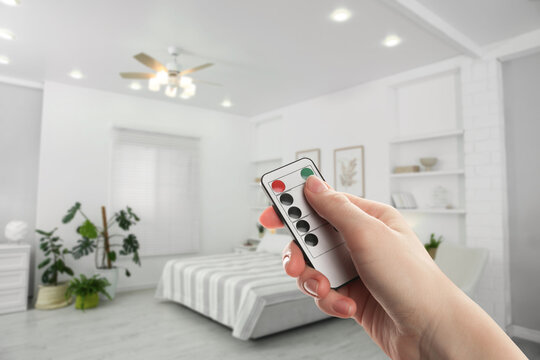 Woman using remote to control lighting in room, closeup