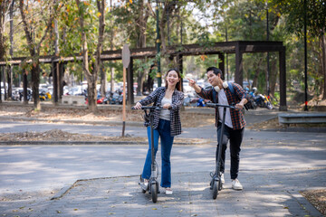 Obraz premium A man and a woman are riding scooters in a park