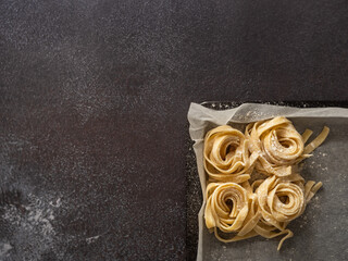 Pasta nests on a kitchen tray with baking paper. Copy space flat lay.