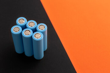 Stack of 18650 cylindrical batteries on black-orange background, rechargeable lithium-ion batteries...