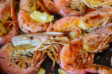 Cooking langoustine on frying pan with butter, lemon and garlic. Fried shrimps.