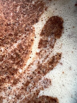 Detalle de polvos de canela con aspecto floral, sobre la espuma del caf&eacute; con leche, primer plano, formato vertical