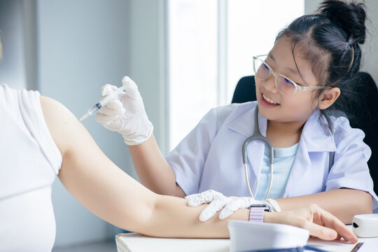 Girl in a doctor's uniform is injecting a syringe into a patient's shoulder
