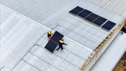 A sustainable energy project featuring solar panels on a roof surrounded by tropical trees,...