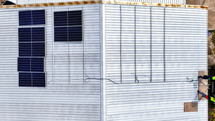 A sustainable energy project featuring solar panels on a roof surrounded by tropical trees,...