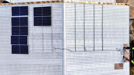 A sustainable energy project featuring solar panels on a roof surrounded by tropical trees,...