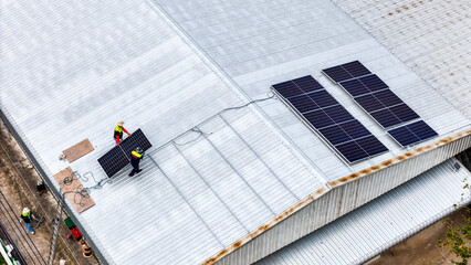 A sustainable energy project featuring solar panels on a roof surrounded by tropical trees,...