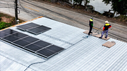 A sustainable energy project featuring solar panels on a roof surrounded by tropical trees,...