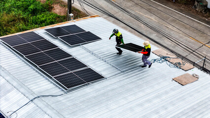 A sustainable energy project featuring solar panels on a roof surrounded by tropical trees,...